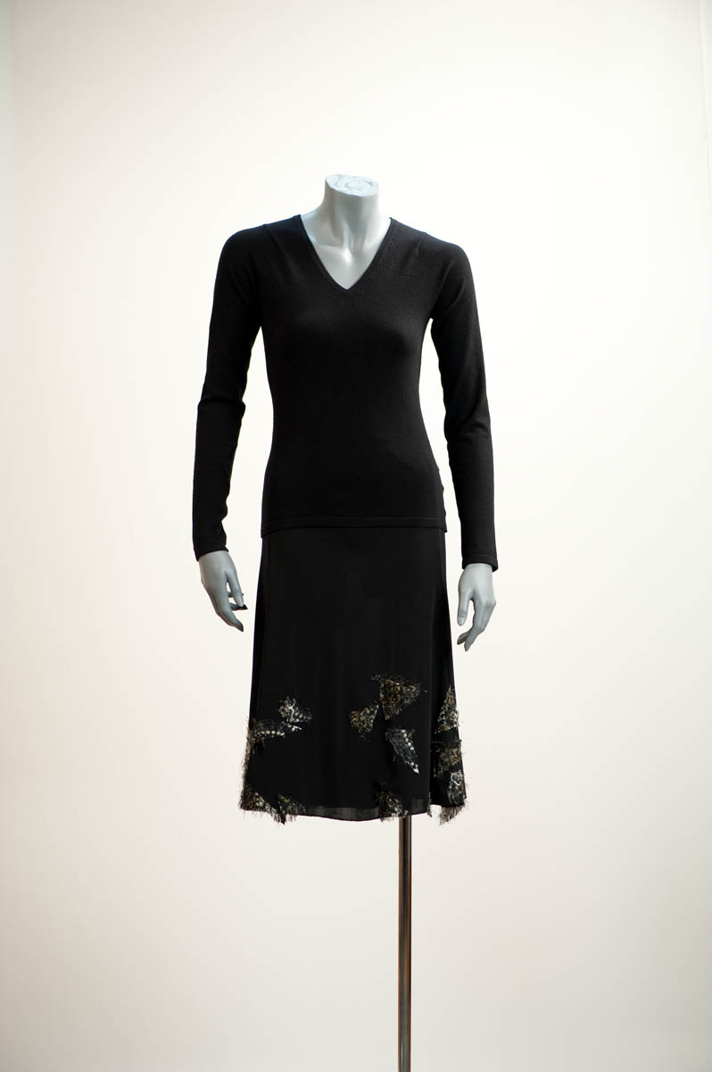 Corsage et jupe en jersey polyester noir crêpé sur lesquels, sont cousus une série de petits triangles irréguliers, poilus ou texturés disposés en carte du ciel sur fond de firmament.  Couleur: noir / Small irregular triangles, tufted and textured, are arranged like constellations in the night sky, sewn onto a skirt and top in black crimped polyester jersey. Colour: black