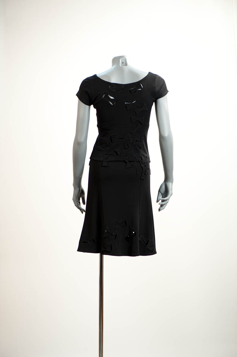 Sur fond ajouré au corsage et jupe en jersey polyester crêpé Couleur: noir / Top with black bows in skin-revealing frames cut out of the fabric, evoking butterflies in flight; skirt in crimped polyester jersey. Colour: black